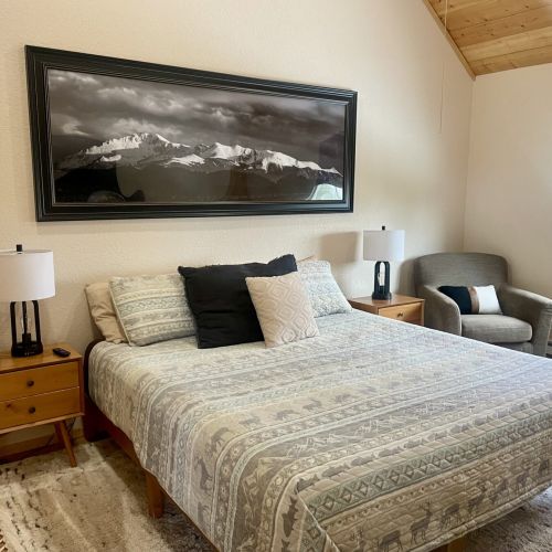 Master bedroom has a king bed, two side tables and a chair