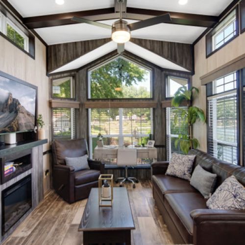 Living room with ample natural light from large windows and a dedicated desk area.