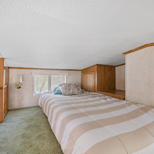 Single loft bed positioned near windows, letting in natural light and providing a view of the surrounding campground.