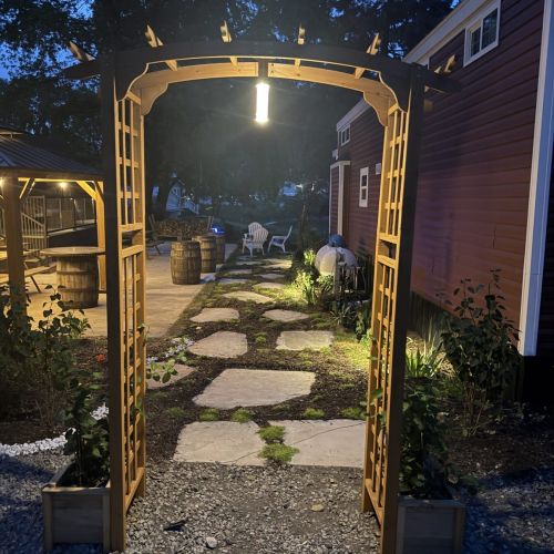 Cozy nighttime ambiance with illuminated stone pathway and arch leading to the cabin.