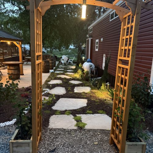 Cozy nighttime ambiance with illuminated stone pathway and arch leading to the cabin.