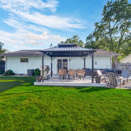 Spacious fenced backyard with deck, Adirondack chairs, and outdoor dining - perfect for grilling, lounging, and making memories under the stars.