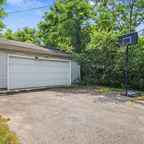 Private driveway and garage area with ample parking, plus a basketball hoop for added outdoor fun and recreation.