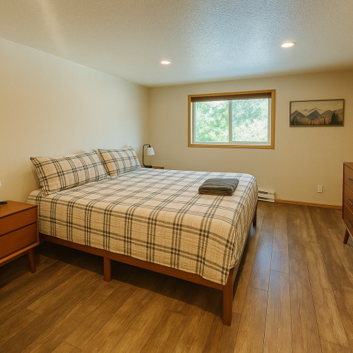 This lower level bedroom has a king bed, a chair, two side tables, smart TV and dresser. There is also an adjoining bathroom.