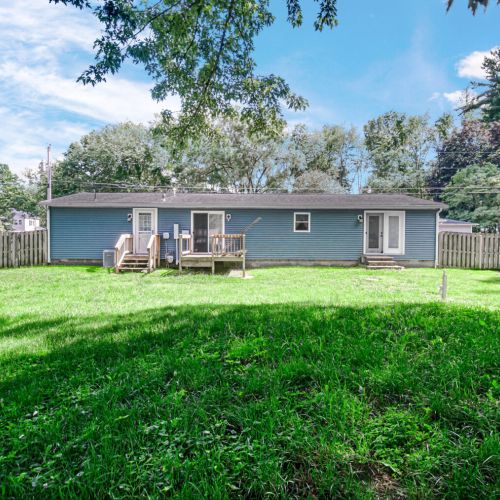 Back exterior view of the home with a fully fenced-in backyard and back porch.