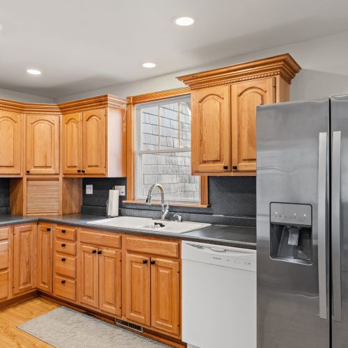 Modern kitchen with a refrigerator, dishwasher, and a sink by the window, perfect for cooking and enjoying natural light.