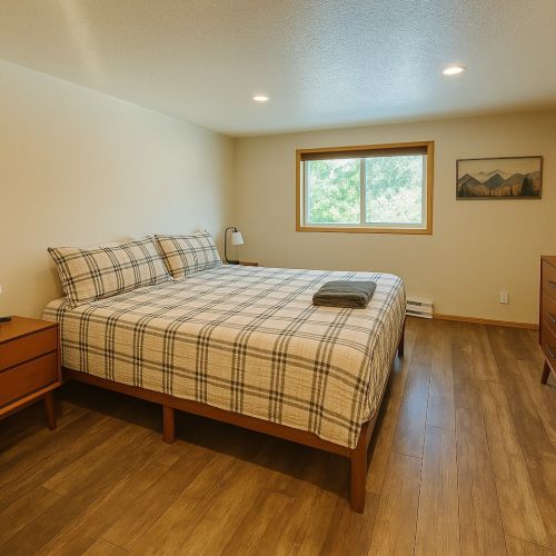 This lower level bedroom has a king bed, a chair, two side tables, smart TV and dresser. There is also an adjoining bathroom.
