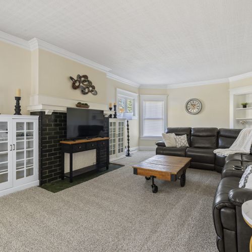 Bright, inviting living space featuring leather sofas, a large TV, and classic charm for comfortable group gatherings.