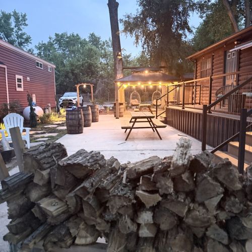Outdoor deck with seating, two picnic tables, birdcage-style swings, and firewood for cozy evening fires.