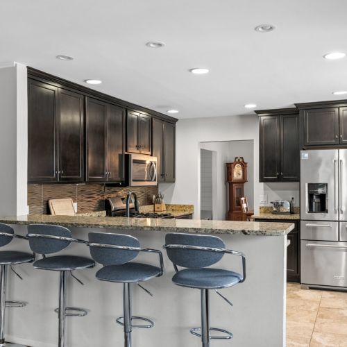 Fully equipped kitchen with stainless steel appliances and seating for 3 people and a bar with 4 stools