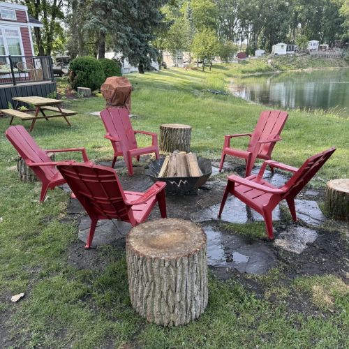 Outdoor space with a fire pit, picnic table, and grill, set against a tranquil lake backdrop.