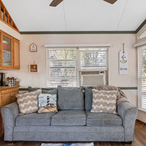 Cozy up on the couch in the open-concept living area, perfect for relaxing after a day at the campground.
