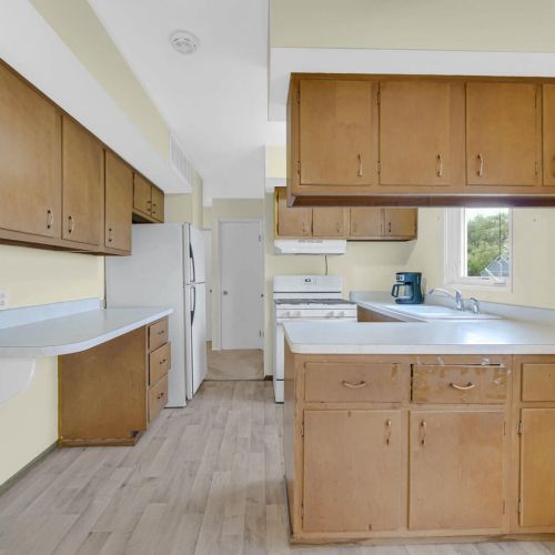 Kitchen with fridge and stove with window at the kitchen sink.