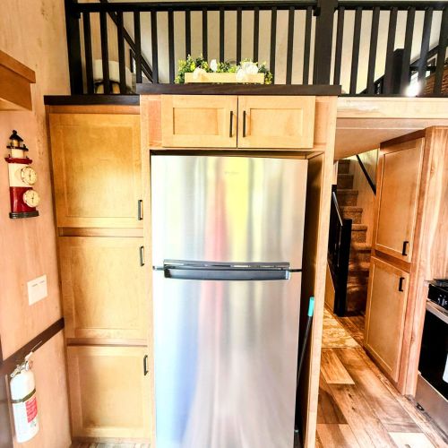 View of the fridge and stairs leading up to the loft in the background.