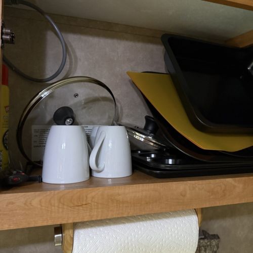Close-up of glasses, utensils, and other kitchen items, showing the fully stocked kitchen for guest convenience.