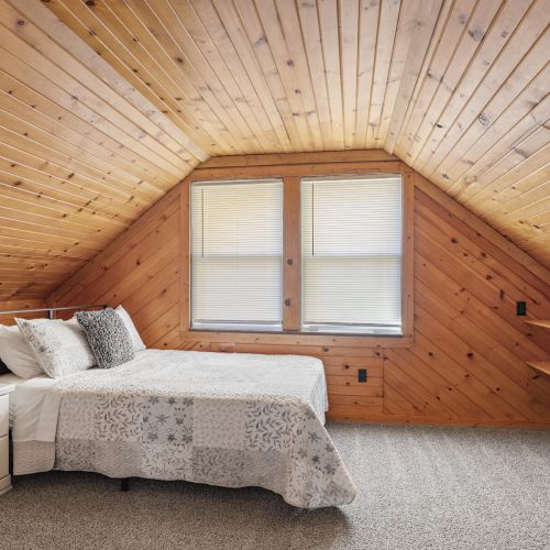 Warm and inviting bedroom with rich wood walls, soft bedding, and a calm atmosphere—perfect for a restful night.