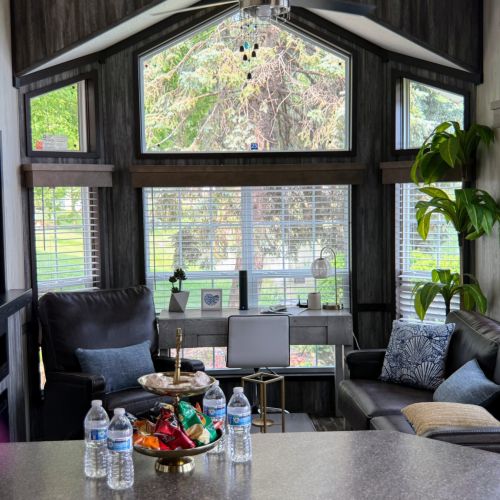 Living room with ample natural light from large windows and a dedicated desk area.