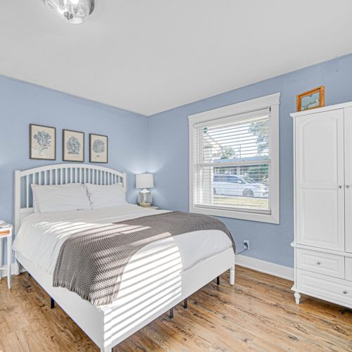 Relax in the primary bedroom featuring plush bedding, Smart TV, and calming coastal tones for a perfect night's rest.