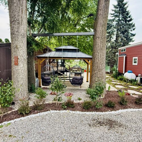 Cabin and grounds as seen from the parking area, featuring lush landscaping and a charming approach.