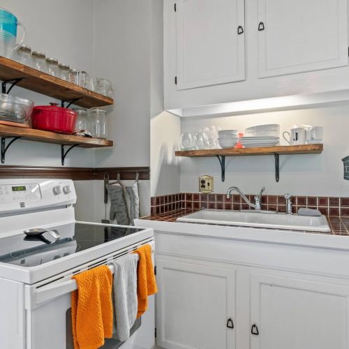 Kitchen with sink, stove and oven. Dishwasher is to the right near the fridge.