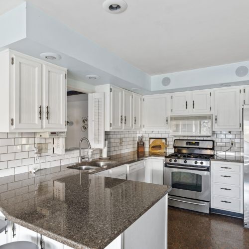 Fully stocked modern kitchen with stainless steel appliances, stone countertops, and breakfast bar.