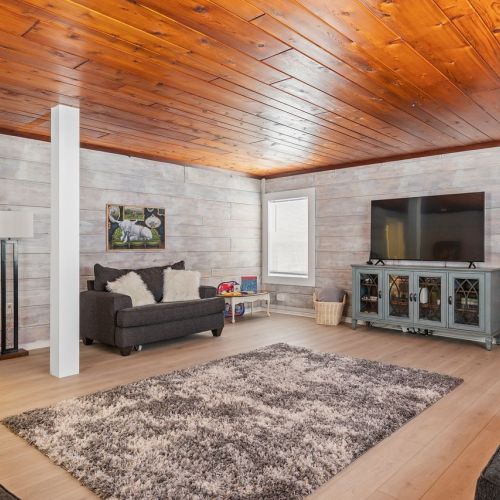 Entertainment-focused living room with a dart board, standalone Mortal Kombat arcade unit, and family-friendly games and books for children.