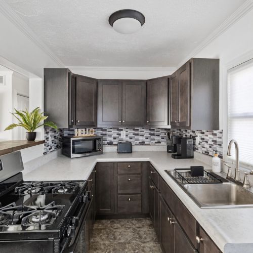 This updated kitchen has a stove, refrigerator, microwave, toaster, crock pot, Keurig coffee maker and a variety of spices.