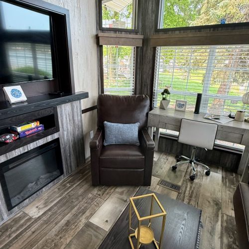Another view of the living area featuring the desk, chair, TV, and large windows.