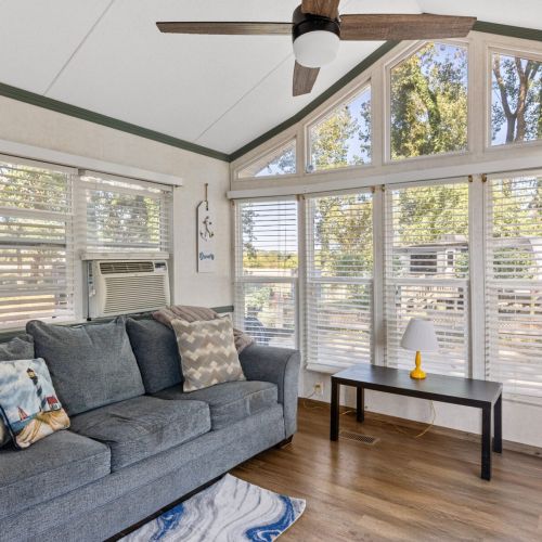 Bright and airy living space with a full wall of windows, letting in plenty of natural light and views of the surrounding nature.