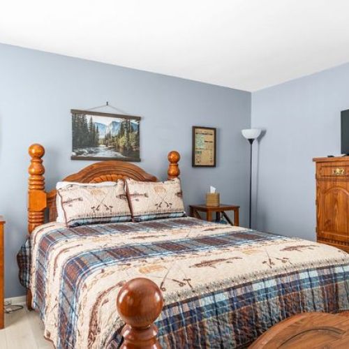 Another view of the master bedroom, showcasing the comfortable bed and wood furnishings.
