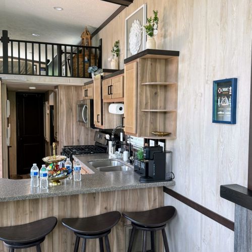 View from the living room into the kitchen, featuring the breakfast bar, loft, and coffee bar area.