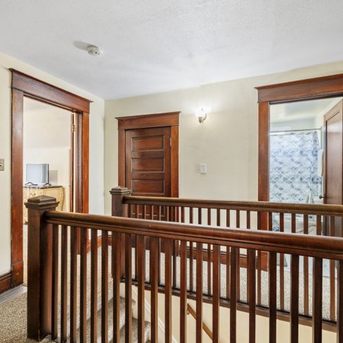 Stairwell with a view into a bedroom and full bathroom, adding an open and inviting feel to the upper level.