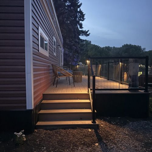 Relax on the deck at night, highlighted by charming lighting for a cozy atmosphere.